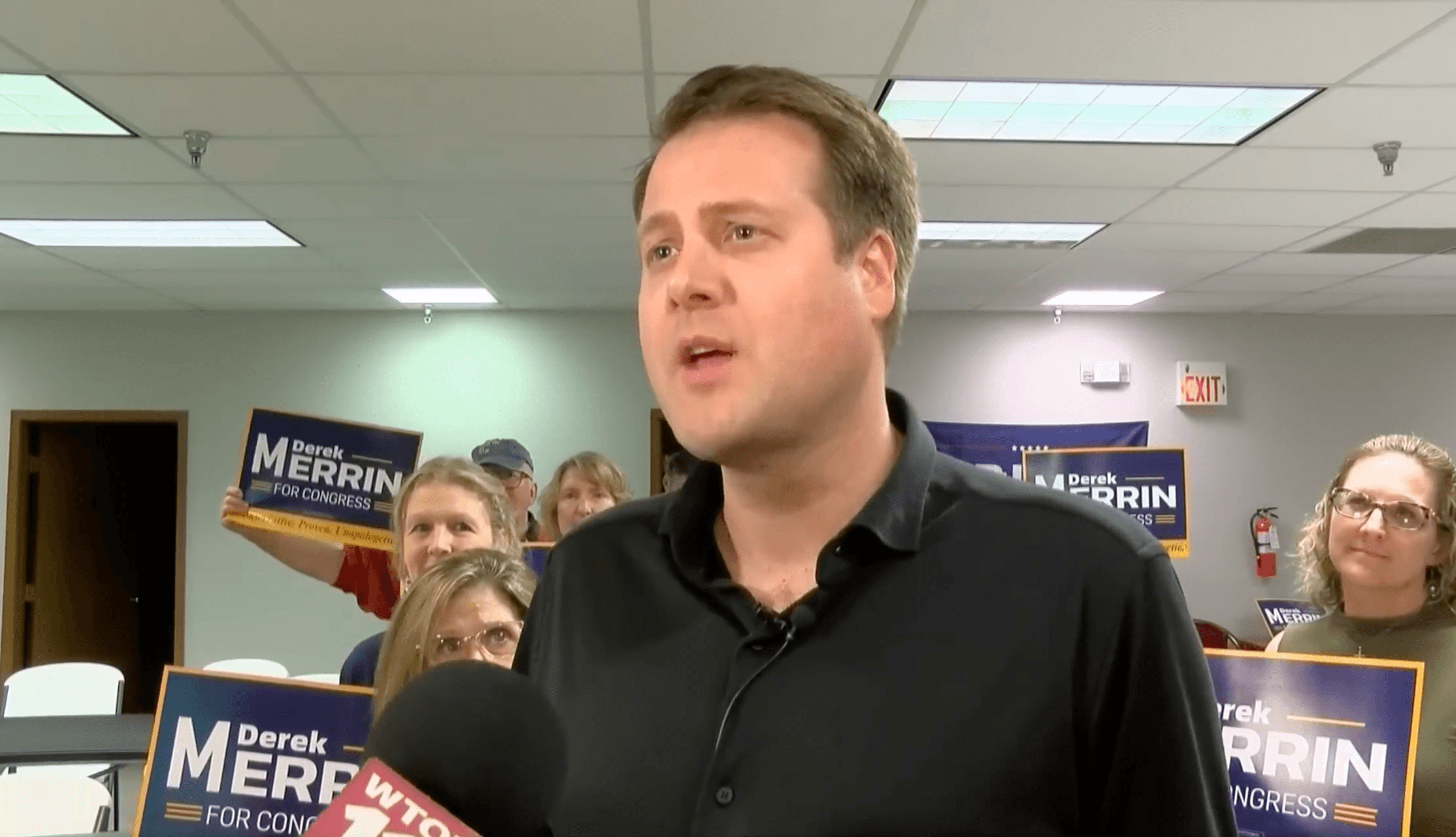 Derek Merrin speaking at a campaign event with Derek Merrin for Congress signs behind him